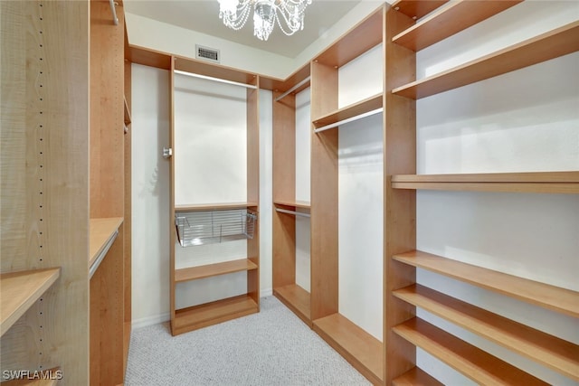 walk in closet with light colored carpet and a notable chandelier