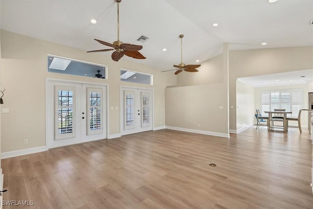 unfurnished living room with ceiling fan, french doors, high vaulted ceiling, and light hardwood / wood-style floors