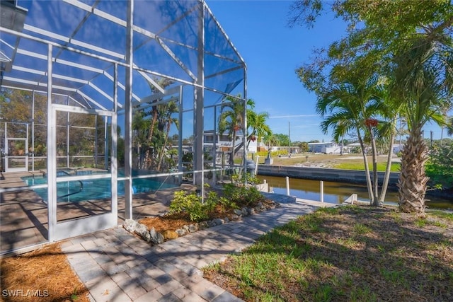 view of pool featuring glass enclosure and a water view