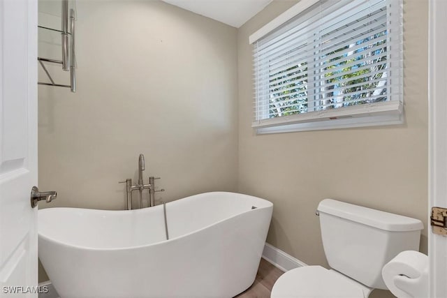 bathroom featuring hardwood / wood-style flooring, toilet, and a bath