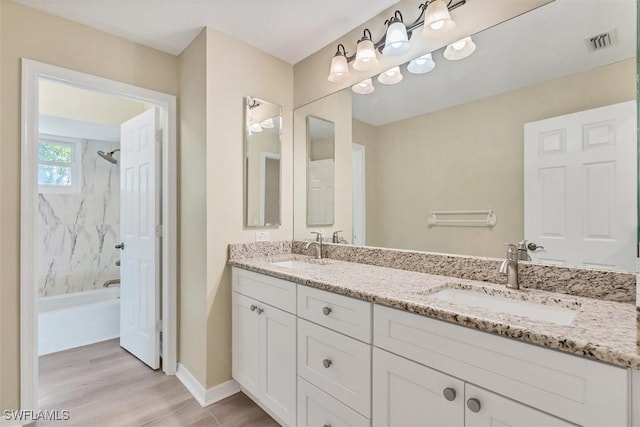 bathroom featuring hardwood / wood-style floors, vanity, and tiled shower / bath