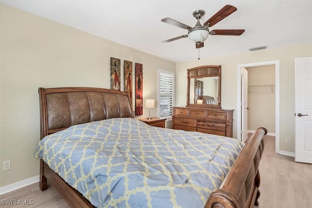 bedroom with ceiling fan, light hardwood / wood-style floors, a walk in closet, and a closet