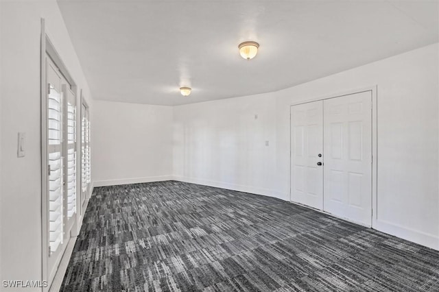 spare room featuring dark colored carpet