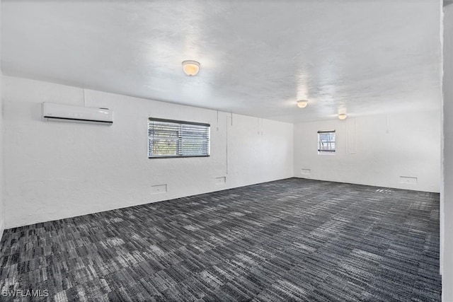 empty room with a wall unit AC and dark carpet