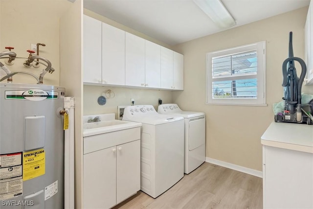 washroom featuring washer and clothes dryer, cabinets, electric water heater, sink, and light hardwood / wood-style floors