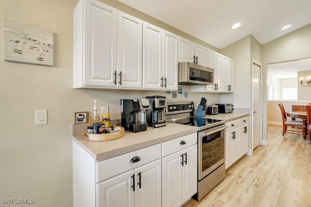 kitchen with a chandelier, appliances with stainless steel finishes, light hardwood / wood-style flooring, and white cabinetry