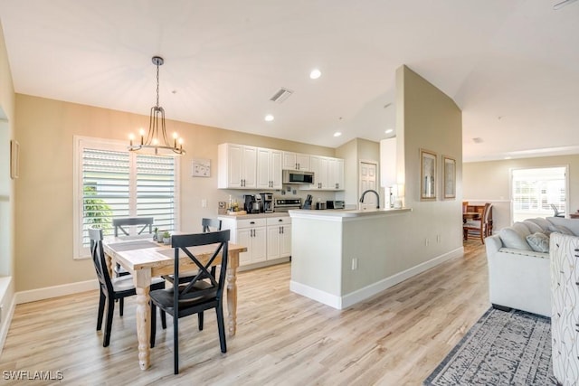 dining space featuring light hardwood / wood-style flooring, a chandelier, and sink