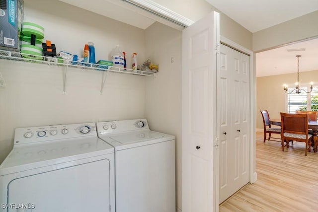 laundry room featuring light hardwood / wood-style floors, washer and clothes dryer, and a notable chandelier