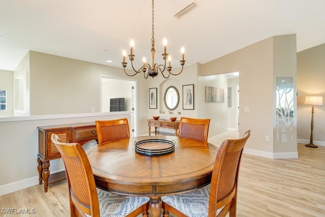 dining space with vaulted ceiling, light hardwood / wood-style flooring, and a chandelier