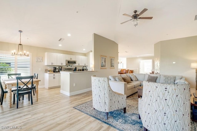 living room featuring sink, ceiling fan with notable chandelier, and light wood-type flooring