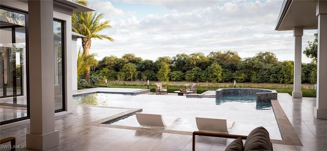 exterior space featuring pool water feature, an in ground hot tub, a patio, and an outdoor fire pit