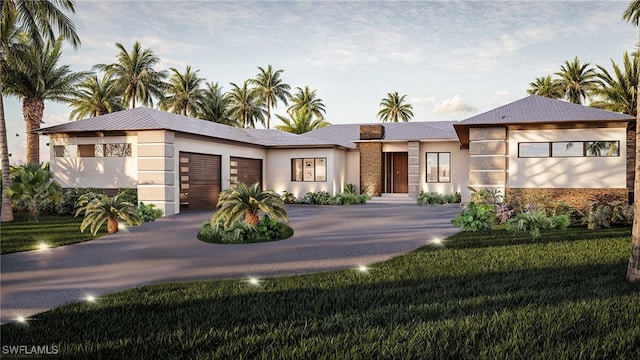 view of front of property featuring driveway, an attached garage, a front lawn, and stucco siding