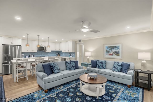 living room with light wood-type flooring, ceiling fan, and crown molding