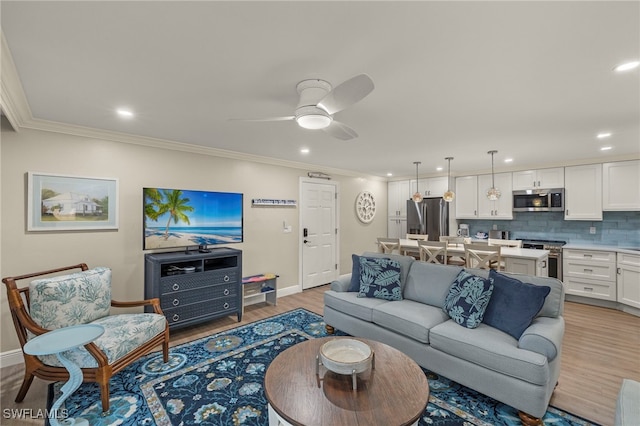 living room featuring ceiling fan, light wood-type flooring, and ornamental molding