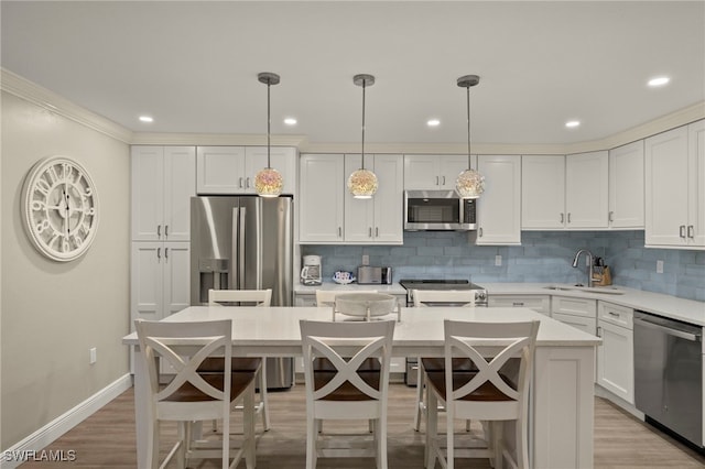 kitchen featuring white cabinetry, appliances with stainless steel finishes, tasteful backsplash, a kitchen island, and pendant lighting