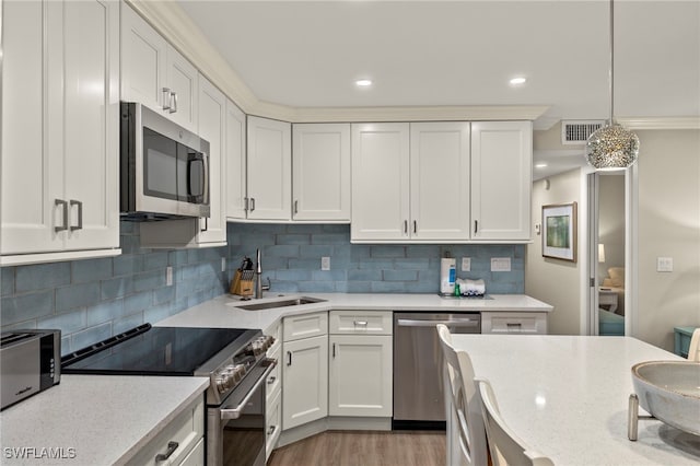 kitchen featuring stainless steel appliances, tasteful backsplash, hanging light fixtures, white cabinets, and sink