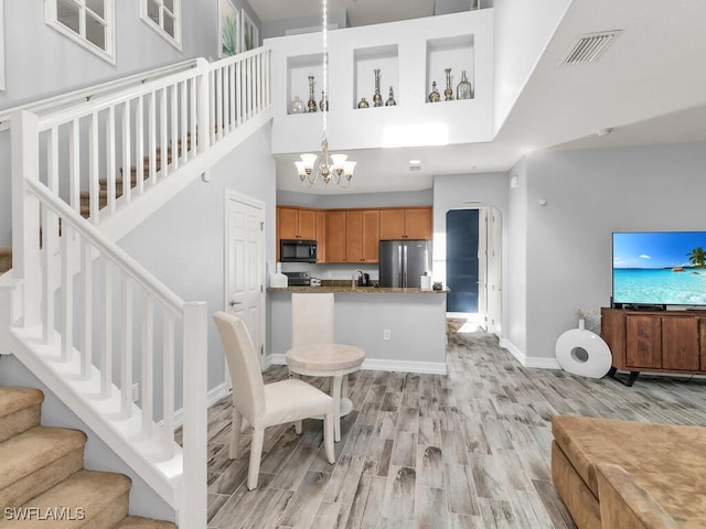 interior space with a chandelier, a towering ceiling, and light hardwood / wood-style flooring