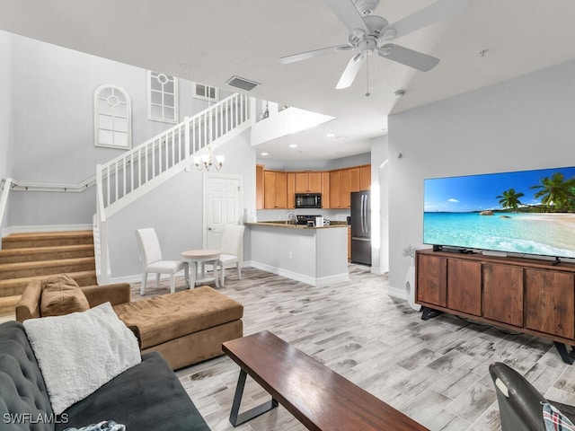 living room featuring ceiling fan with notable chandelier, light hardwood / wood-style floors, and sink