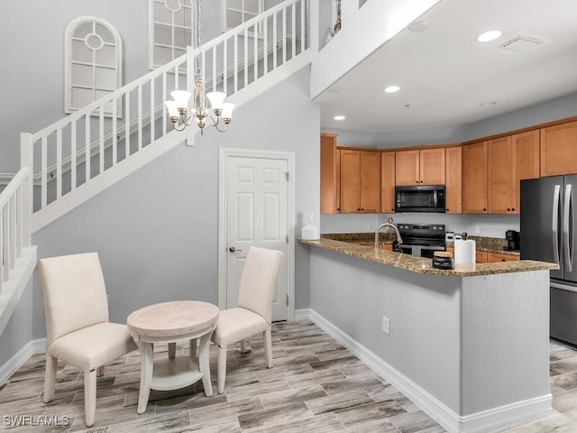 kitchen featuring light hardwood / wood-style flooring, appliances with stainless steel finishes, decorative light fixtures, light stone counters, and kitchen peninsula