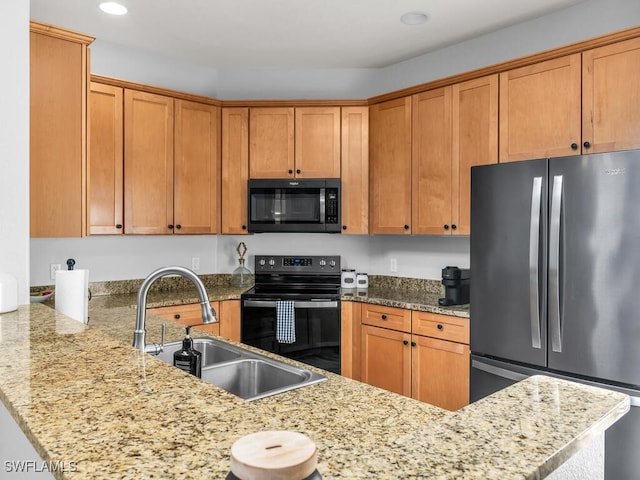 kitchen featuring black appliances, light stone counters, kitchen peninsula, and sink