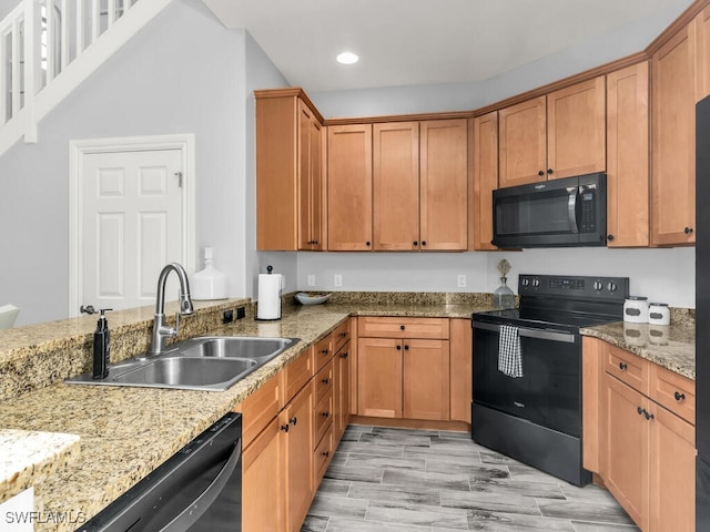 kitchen featuring light stone countertops, sink, and black appliances