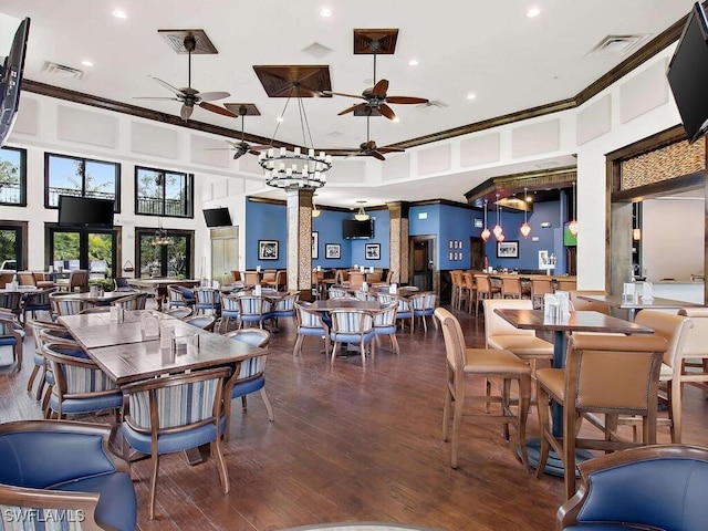 dining space with dark hardwood / wood-style flooring, ornamental molding, a high ceiling, and decorative columns