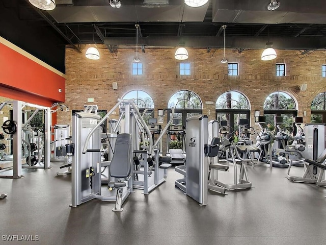 workout area featuring brick wall and a high ceiling