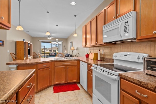 kitchen with sink, tasteful backsplash, decorative light fixtures, kitchen peninsula, and white appliances