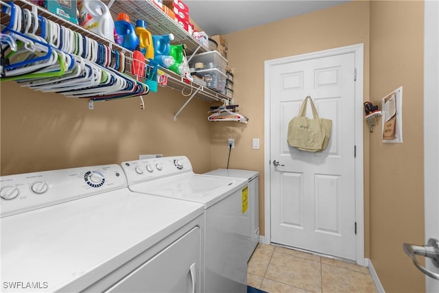 laundry area with independent washer and dryer and light tile patterned floors