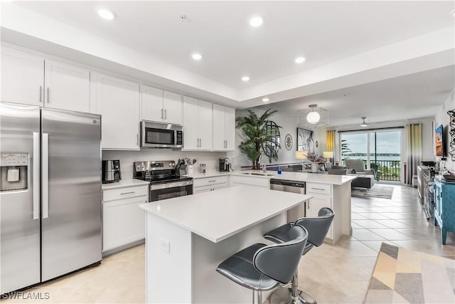 kitchen with a breakfast bar, sink, a kitchen island, white cabinetry, and stainless steel appliances