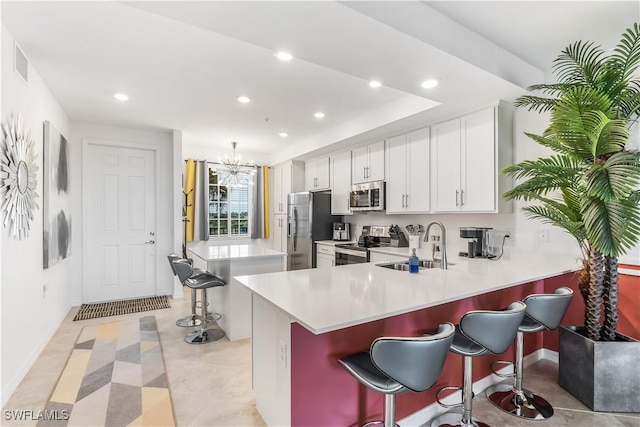 kitchen with kitchen peninsula, stainless steel appliances, sink, white cabinets, and a breakfast bar area