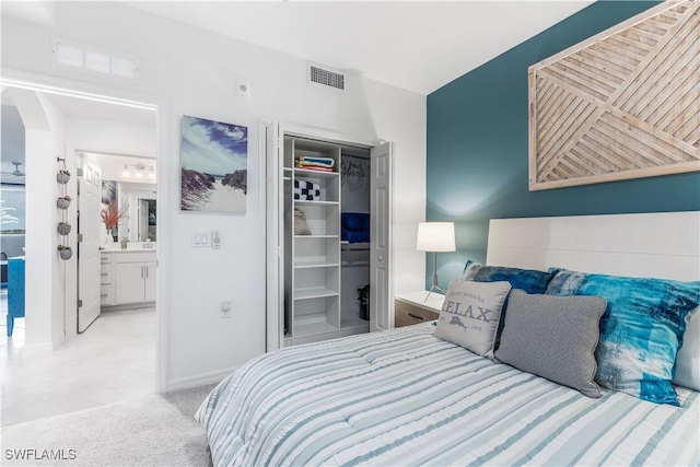 carpeted bedroom with ensuite bathroom and a closet