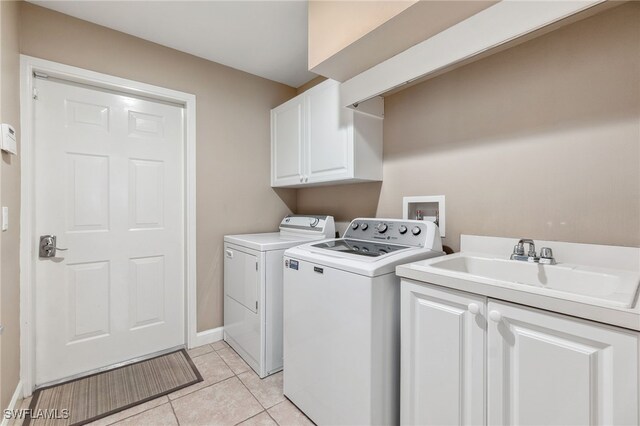 laundry area with washing machine and clothes dryer, sink, light tile patterned flooring, and cabinets