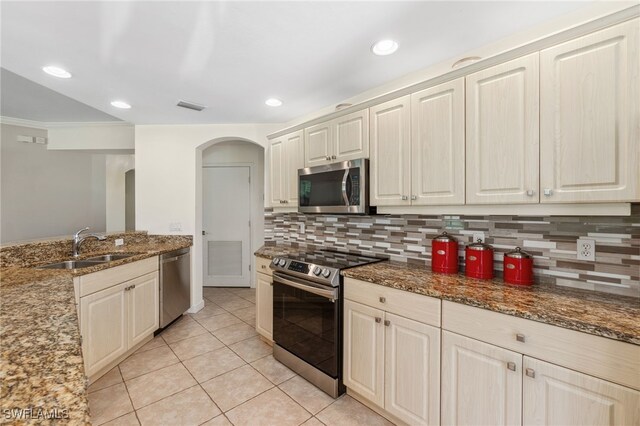 kitchen with backsplash, sink, light stone countertops, appliances with stainless steel finishes, and light tile patterned flooring