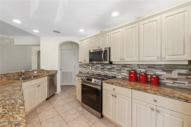 kitchen with visible vents, a sink, stone countertops, appliances with stainless steel finishes, and decorative backsplash