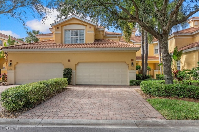 mediterranean / spanish-style house with a tile roof, decorative driveway, a garage, and stucco siding