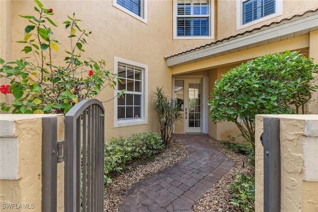 view of exterior entry featuring a gate and stucco siding