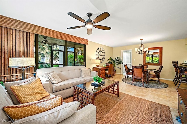 living area with baseboards, light tile patterned flooring, and ceiling fan with notable chandelier