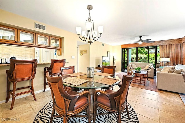 dining space with ceiling fan with notable chandelier, visible vents, baseboards, and light tile patterned flooring