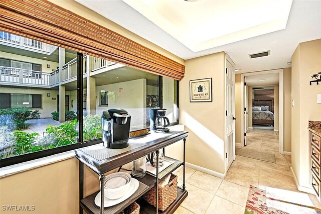 hallway featuring baseboards, visible vents, and light tile patterned flooring