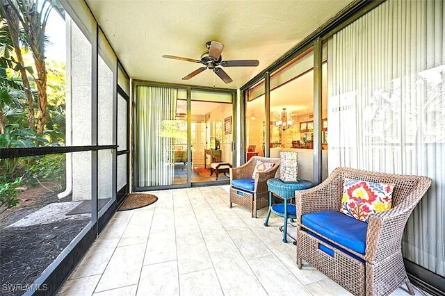 sunroom featuring ceiling fan with notable chandelier and plenty of natural light