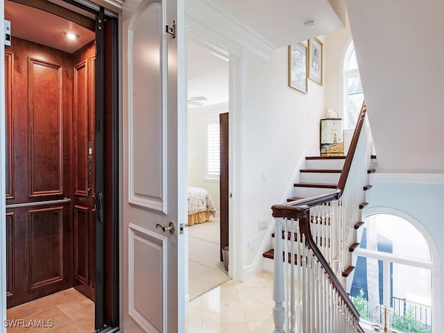 stairs featuring tile patterned floors, a healthy amount of sunlight, and crown molding