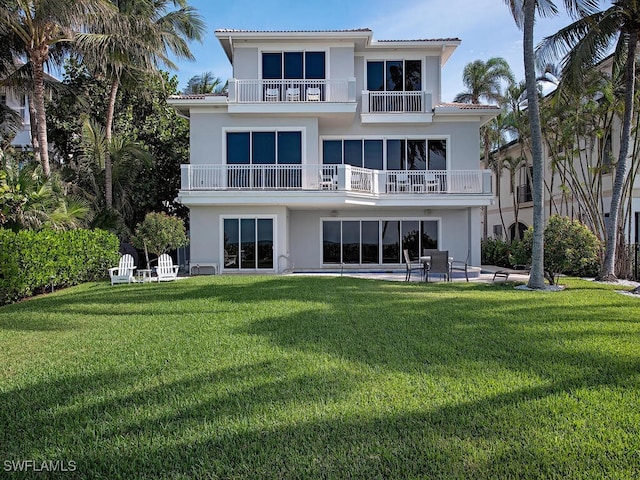 rear view of property featuring a balcony, a yard, and a patio