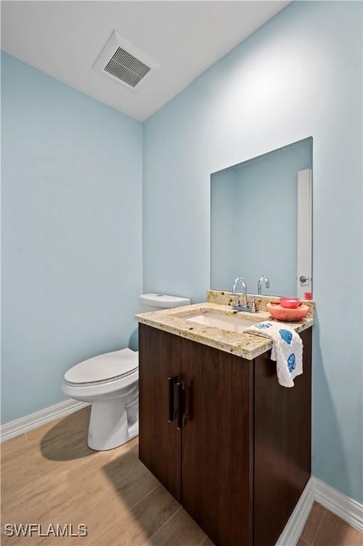 bathroom featuring vanity, wood-type flooring, and toilet