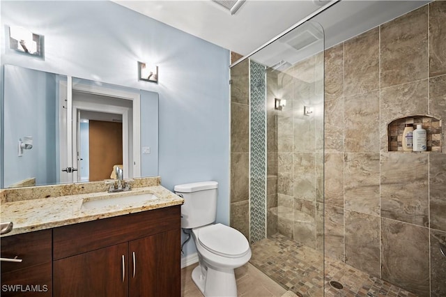 bathroom featuring vanity, tiled shower, and toilet