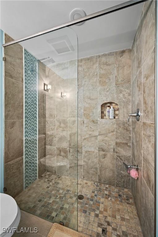 bathroom featuring toilet and a tile shower