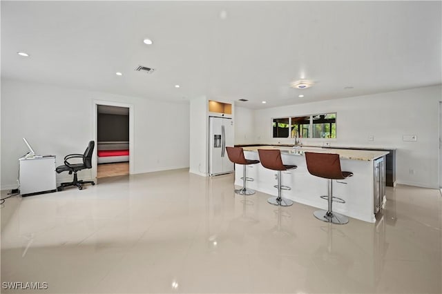 kitchen with a kitchen island, a breakfast bar, and fridge with ice dispenser