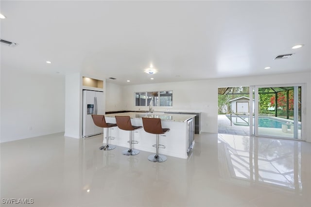 kitchen featuring built in refrigerator, sink, a center island, and a breakfast bar area