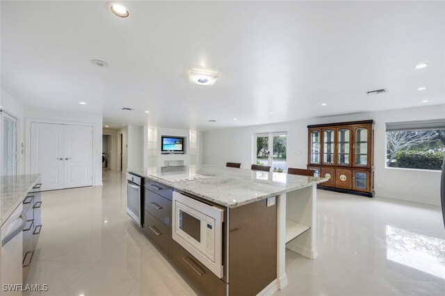 kitchen with light stone countertops, a center island, and white appliances