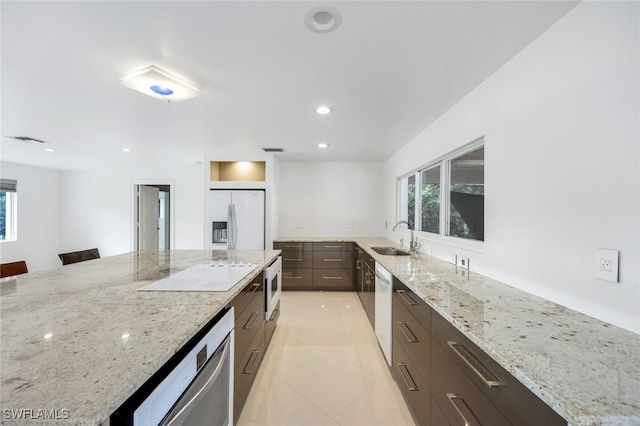 kitchen featuring sink, light stone counters, white appliances, and a breakfast bar